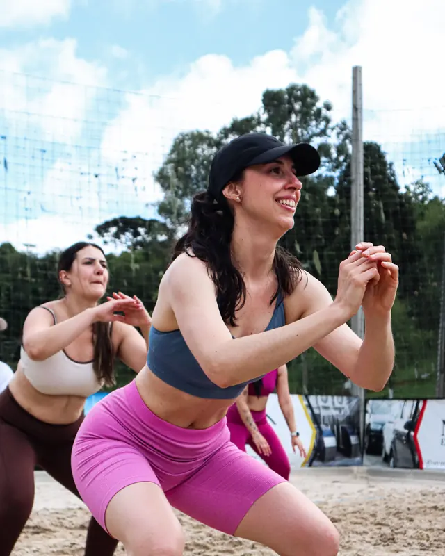 Mulheres fazendo agachamento num treino funcional na areia